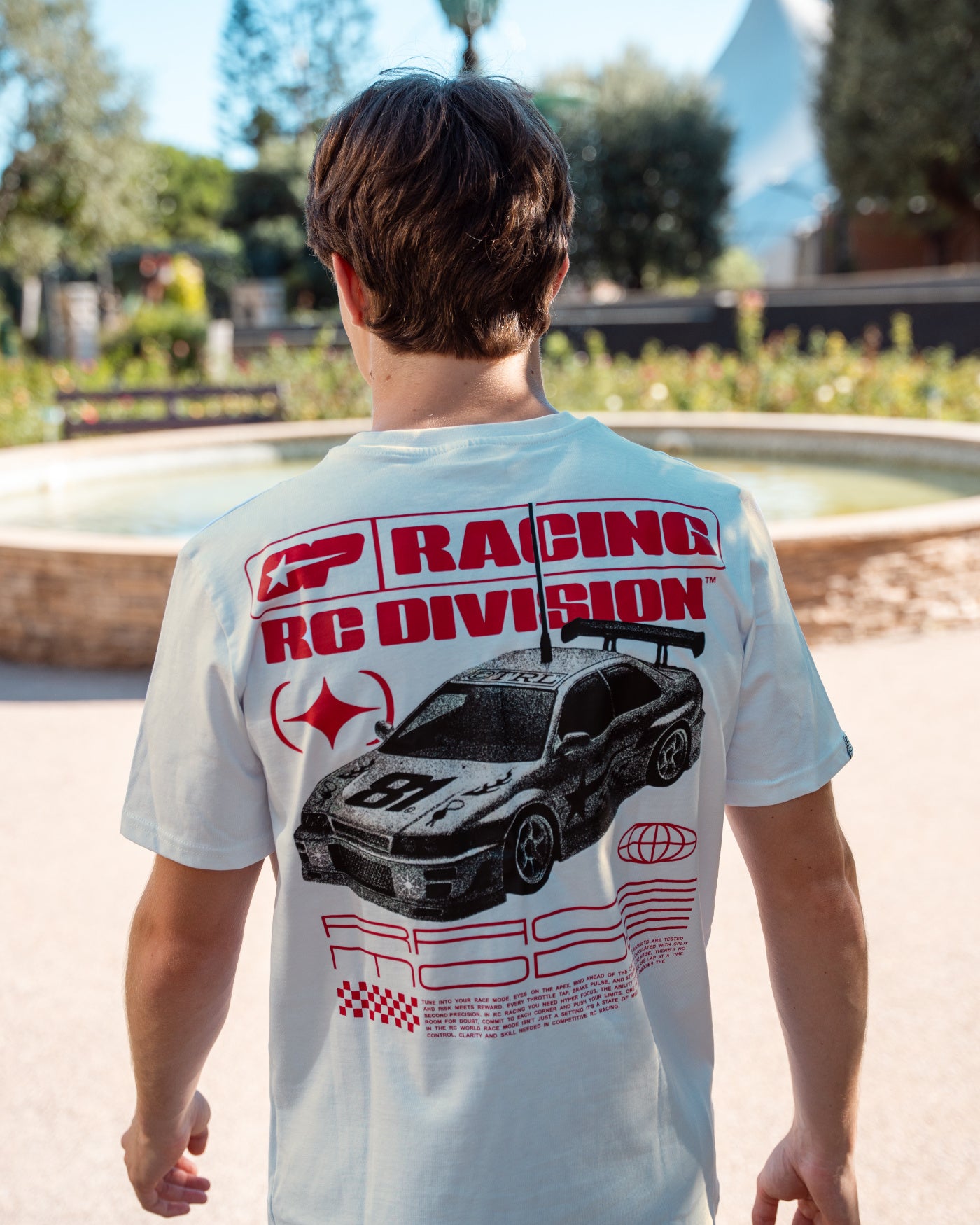81 CLUB Origins T-Shirt - Off White featuring RC car design on back, worn by Oscar outdoors.