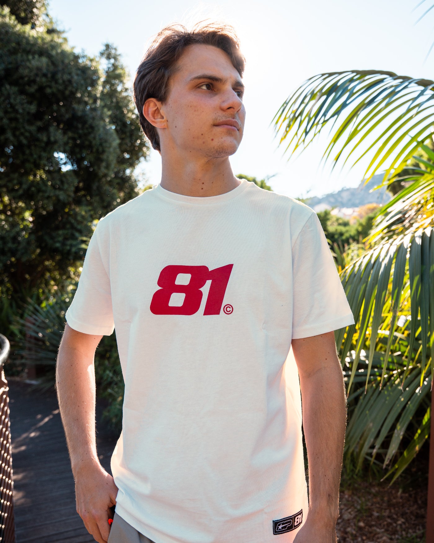 81 CLUB Origins T-Shirt - Off White worn by Oscar in a sunny outdoor setting, featuring the 81 logo.