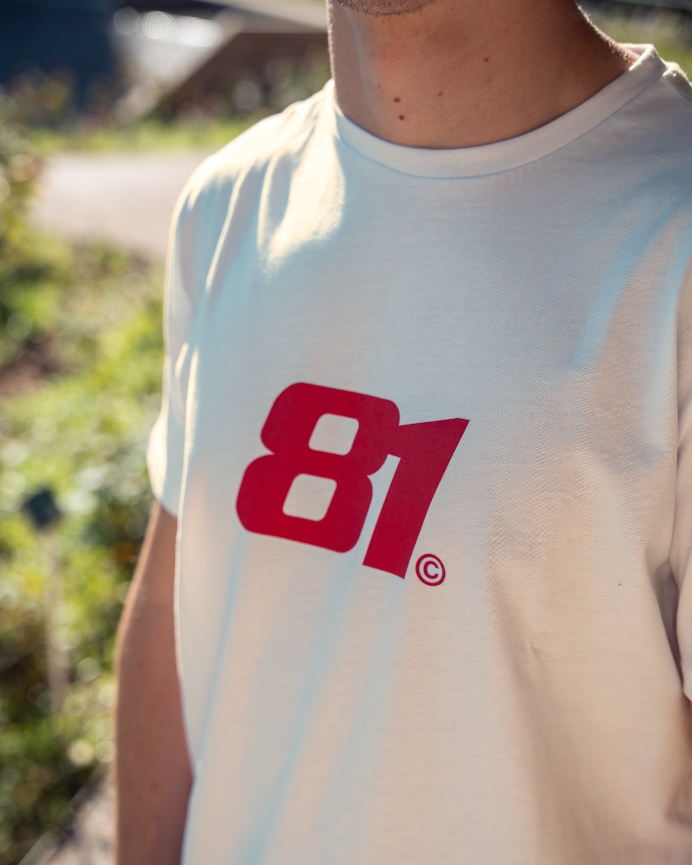 81 CLUB Origins T-Shirt - Off White featuring 81 logo on the front, worn by Oscar outdoors.