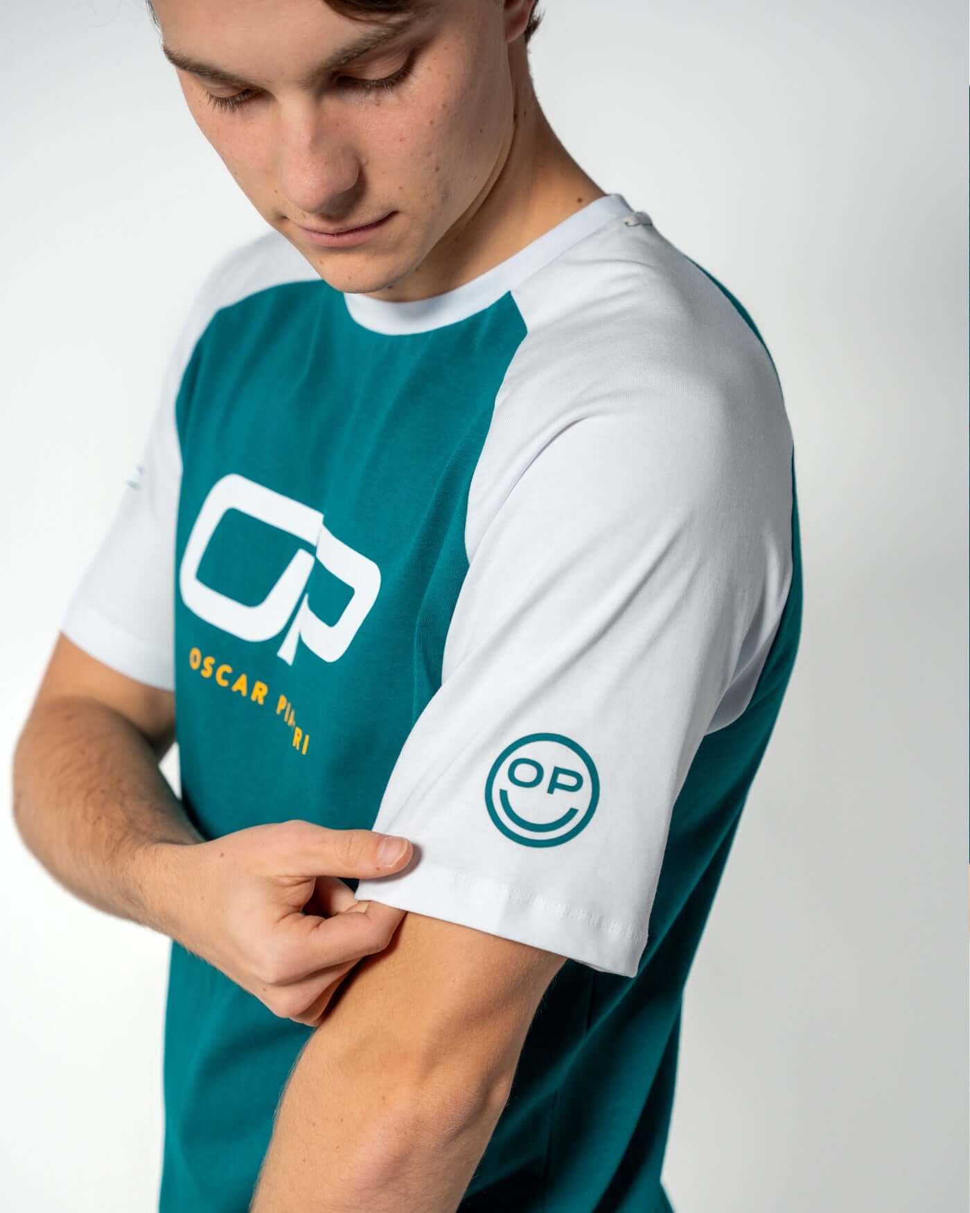 Home Race '26 T-Shirt - Green worn by Oscar showcasing its bold design and OP smiley motif.