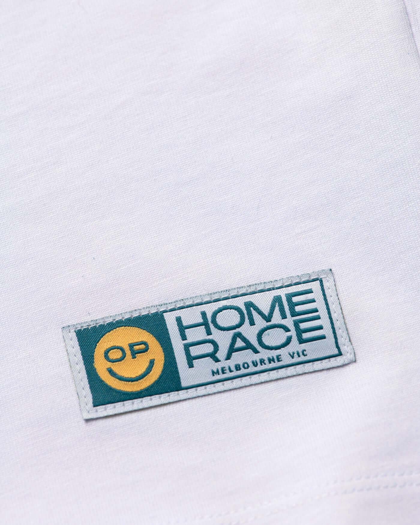 Home Race '26 T-Shirt - White label design with OP smiley icon and Melbourne VIC text.