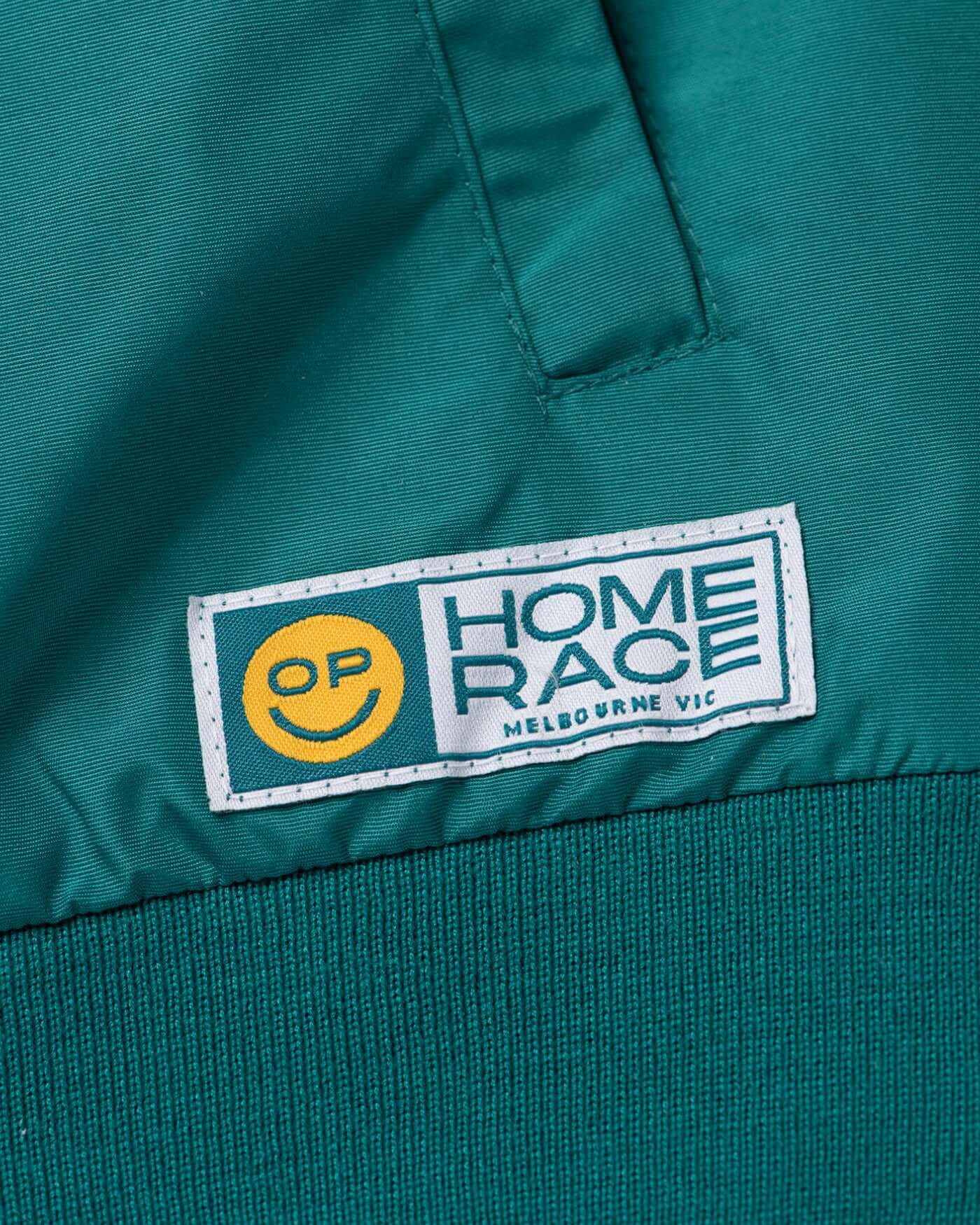 Detail of the Home Race '26 Race Jacket showcasing OP logo and vibrant green fabric.