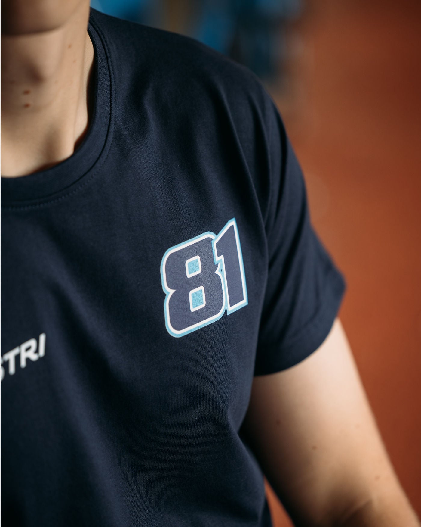 Close-up of black Piastri 81 t-shirt with white race number 81 and part of the name Piastri shown on the front.