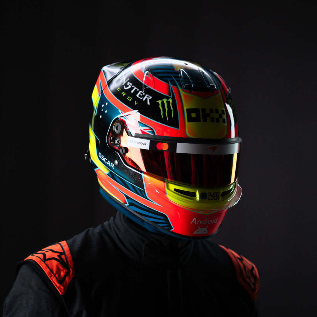 Colorful racing helmet with Monster Energy logo, worn by a driver in a dark setting.