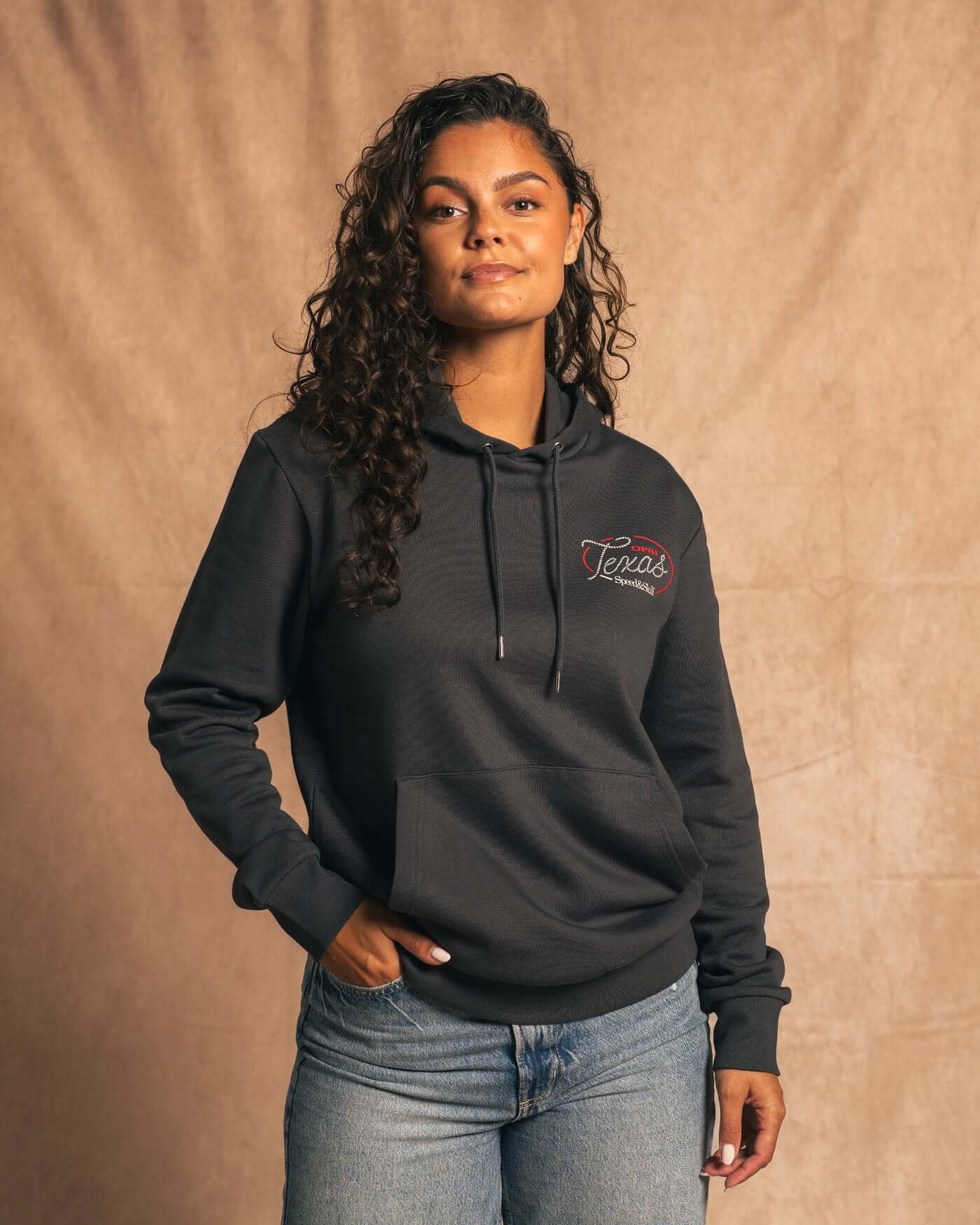 Person wearing Texas 2024 Hoodie in Asphalt, featuring bold Texas-inspired graphics, blending Formula 1 racing and Wild West style.