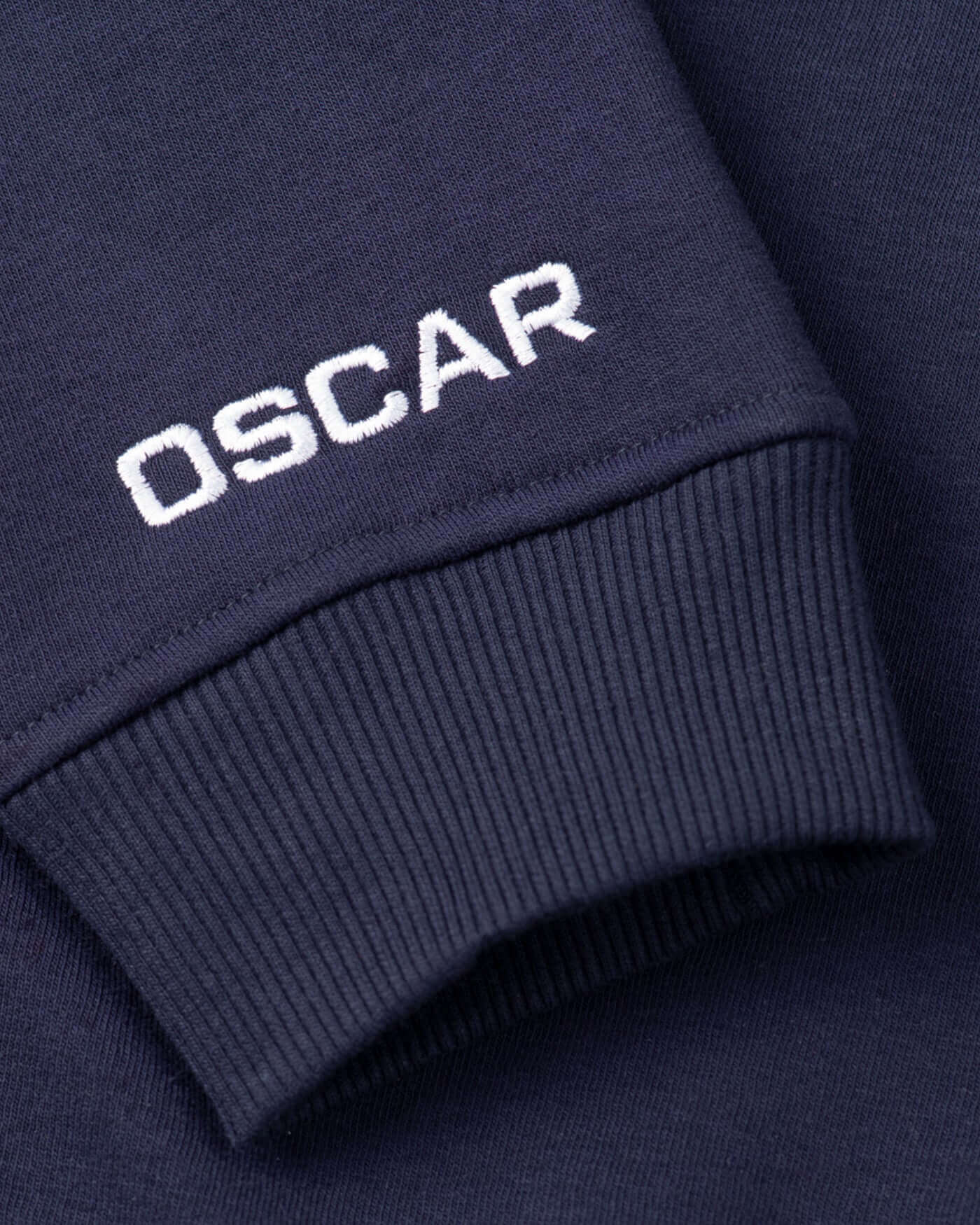 Close-up of the navy OP81 Signature Hoodie featuring Oscar's embroidered logo on the cuff.