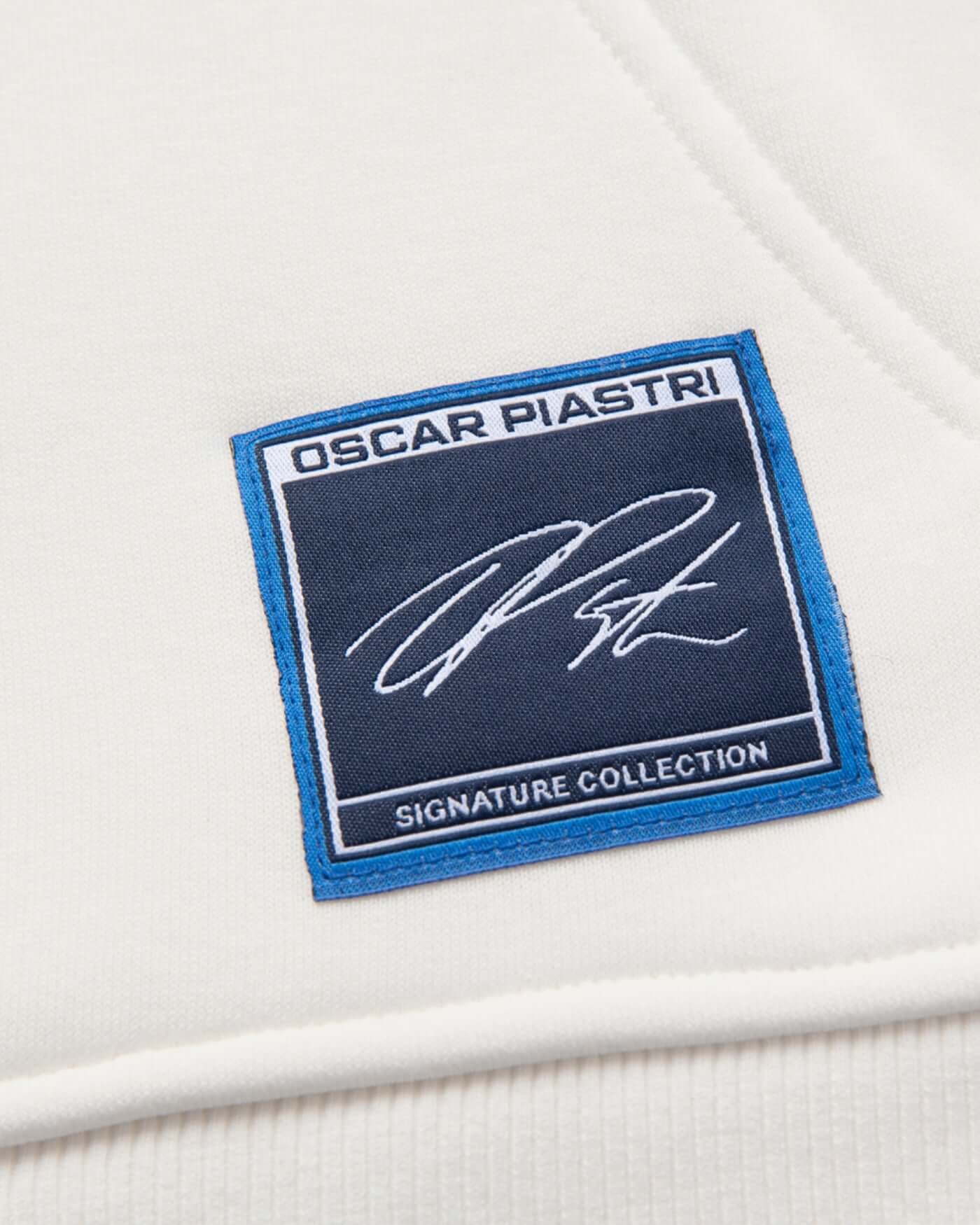 Close-up of the Oscar Piastri logo patch on the Signature Oversized Hoodie - Off White.