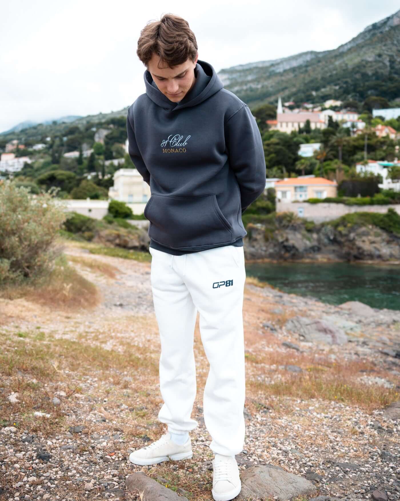 Signature Joggers - Off White worn by a young man outdoors, showcasing comfort and style with a playful twist.