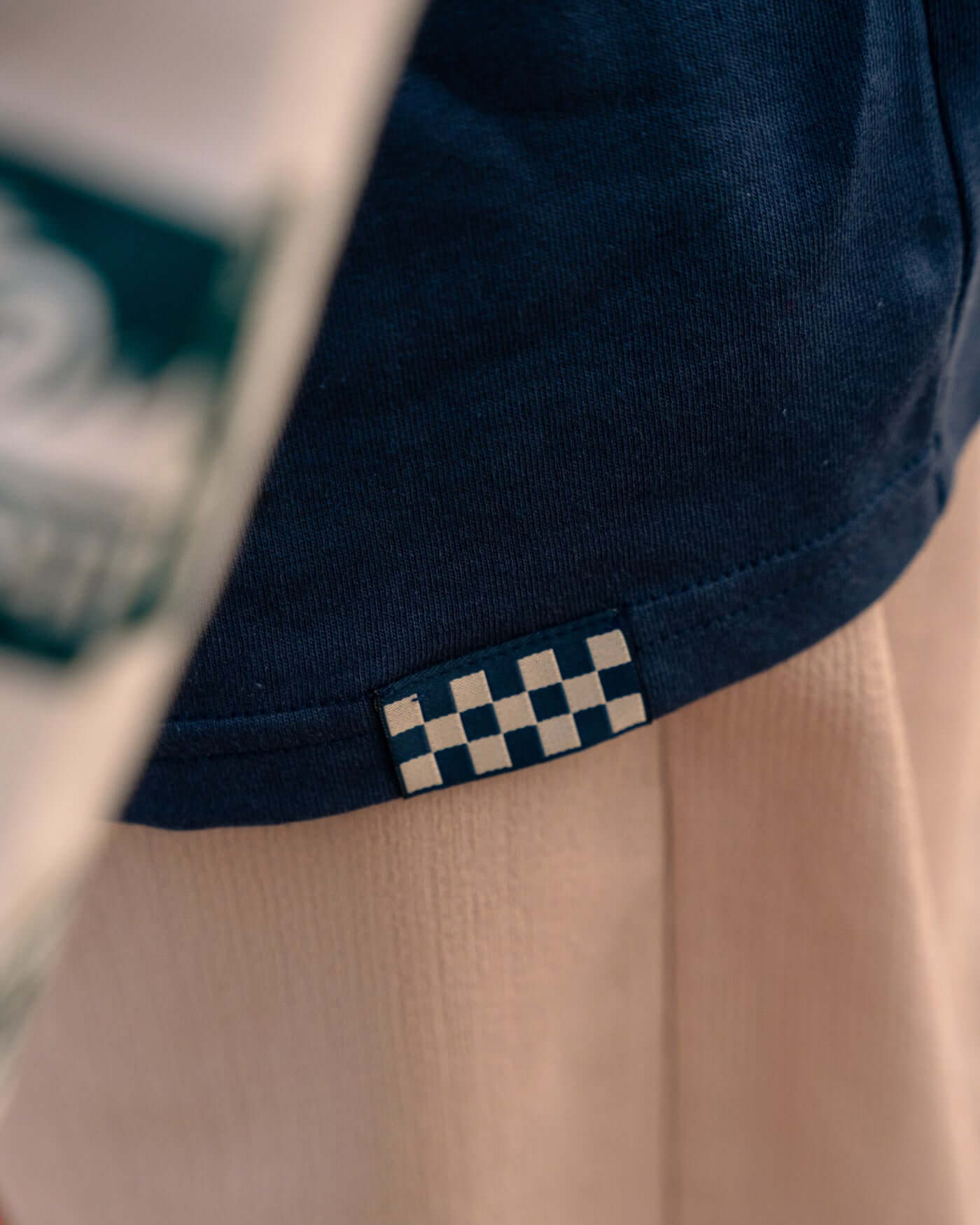 Detail of the World Circuit Layered T-Shirt - Blue showcasing the checkered logo tag.