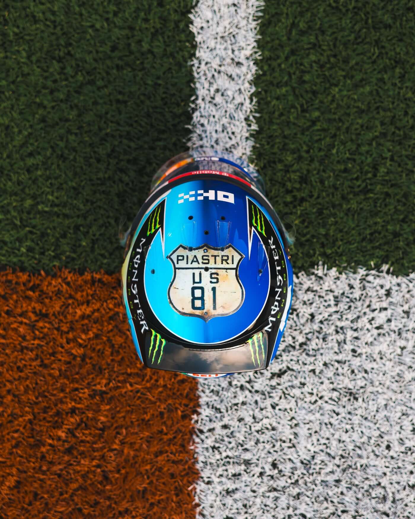 1:2 scale replica of Oscar Piastri's 2024 US Grand Prix helmet on grass, featuring intricate design and Piastri's name.