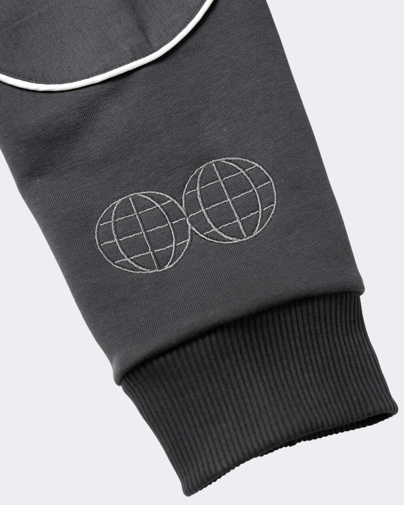 Close-up of the OP81 Origins Hoodie - Asphalt sleeve featuring a dual globe embroidered design.