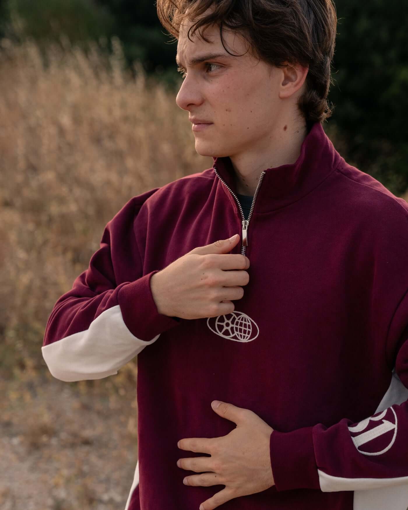 Model wearing World Circuit Quarter Zip - Burgundy standing outdoors with off-white side panels.