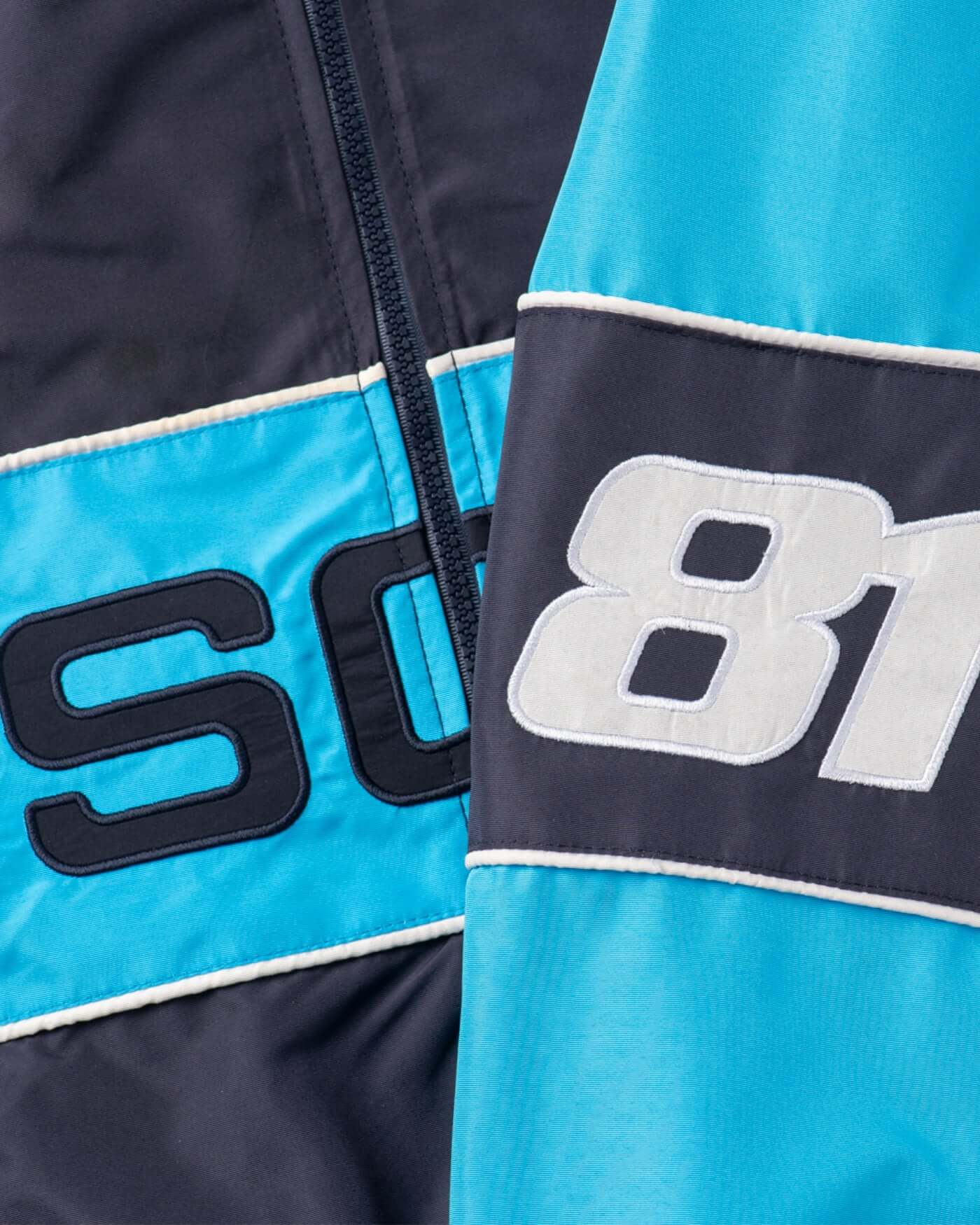 Close-up of Oscar's Signature Racing Jacket showcasing the iconic OP logo and 81 race number in navy and light blue accents.