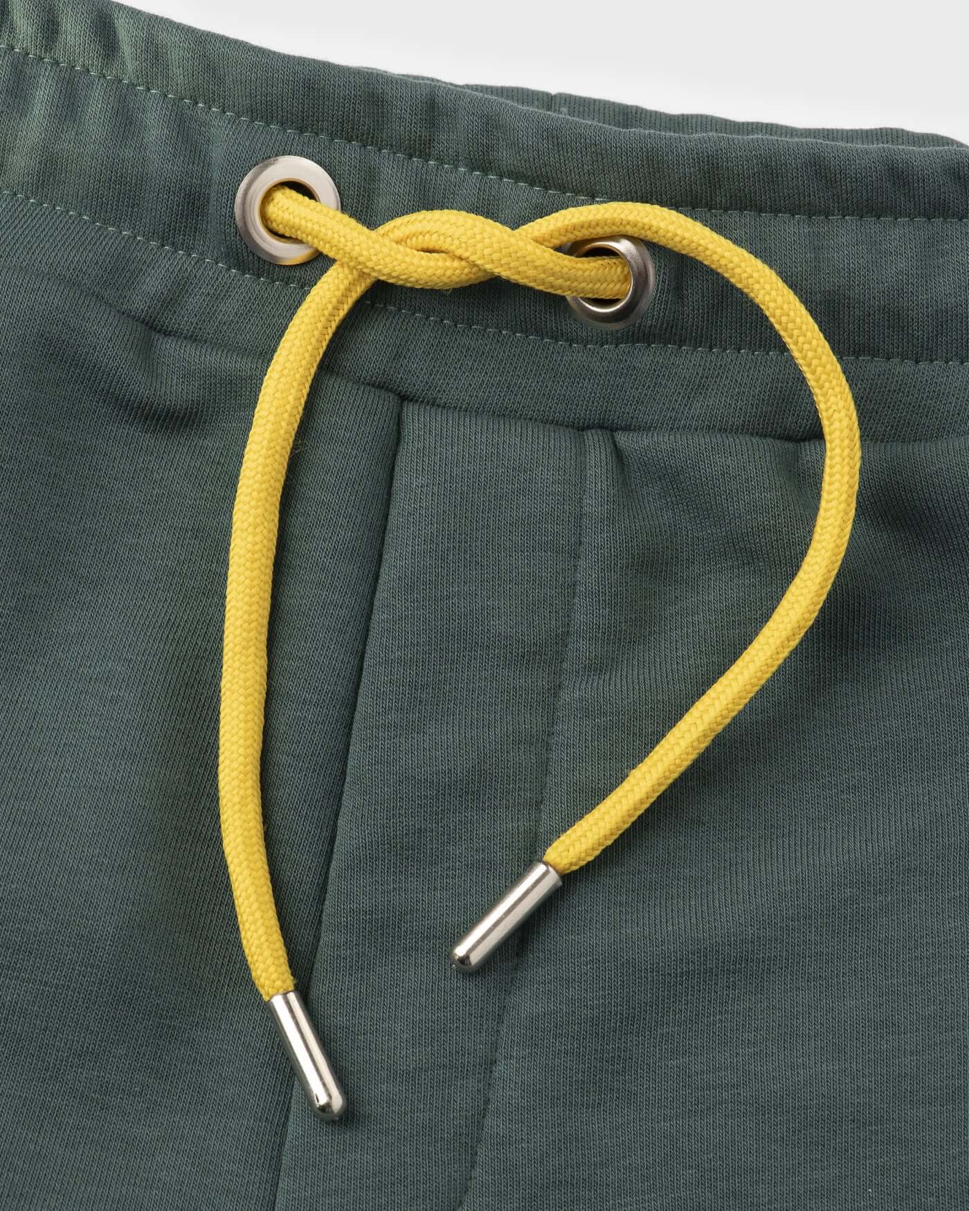 Close-up of green shorts waistband with yellow drawstring, showcasing sporty design for race day.