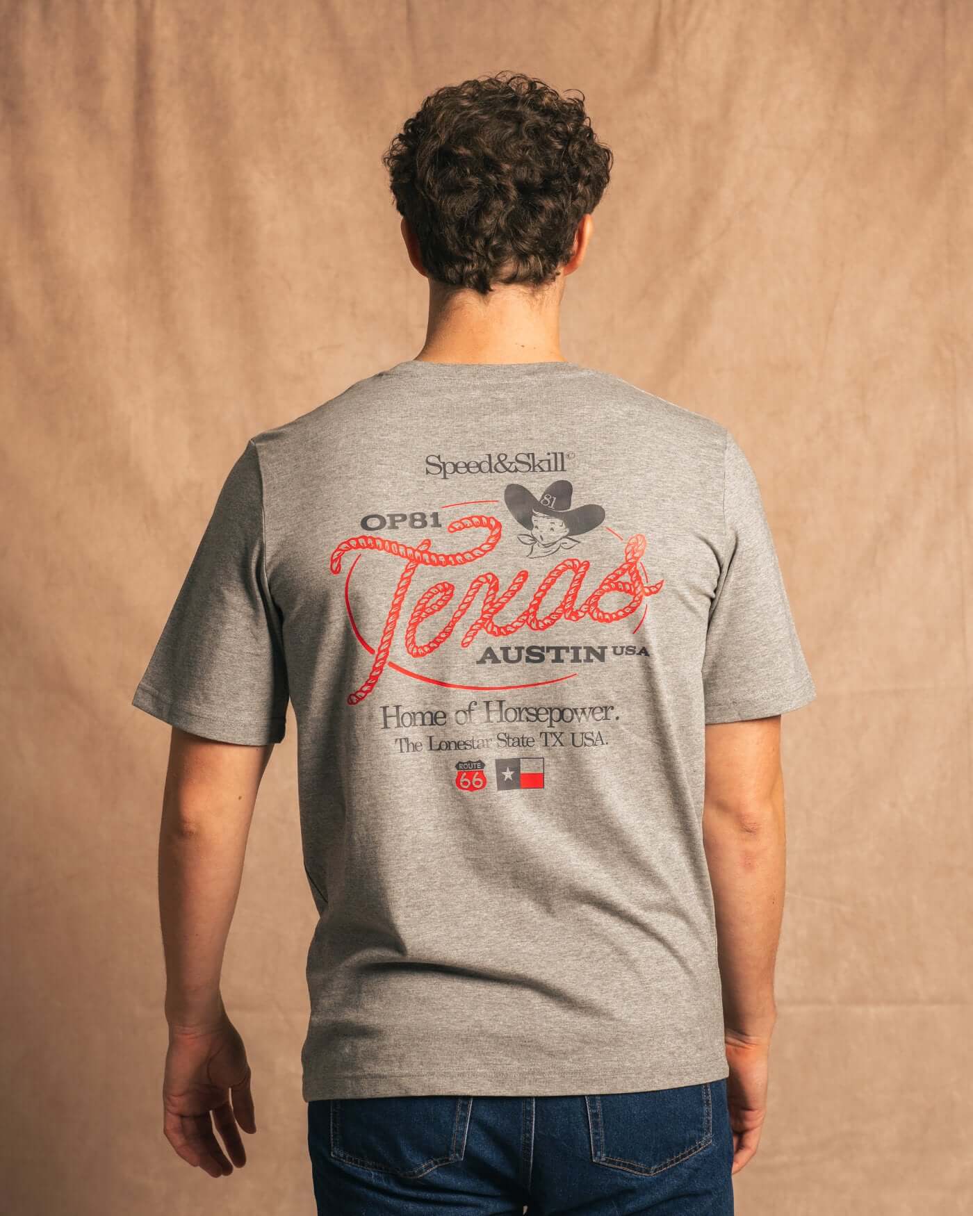 Man wearing Texas 2024 T-Shirt in light grey, featuring bold Texas-inspired graphics and nods to Formula 1 racing and Western culture.