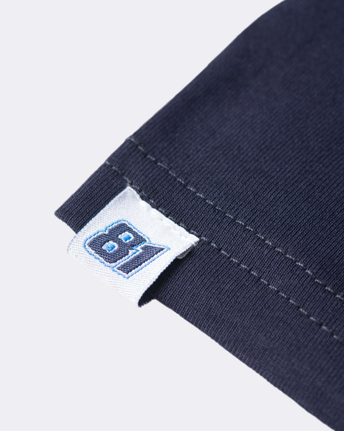 Close-up of the navy kids t-shirt's label featuring race number 81 and quality stitching details.
