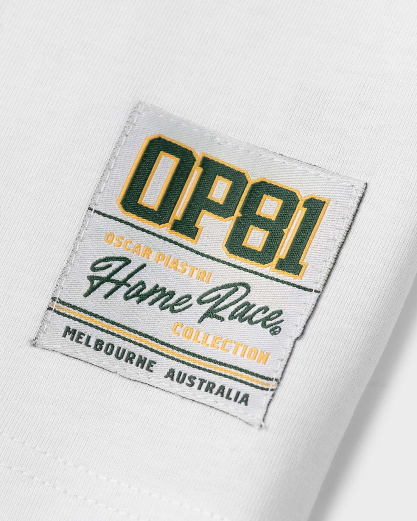 Oscar Piastri Home Race Collection label on a white t-shirt, featuring vibrant green and gold colors.