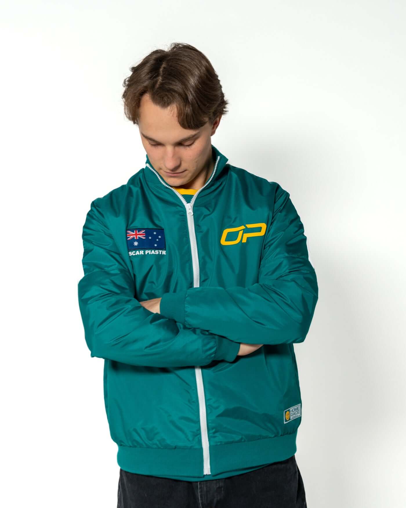 Home Race '26 Race Jacket modeled by Oscar Piastri, featuring Aussie pride in green and gold.