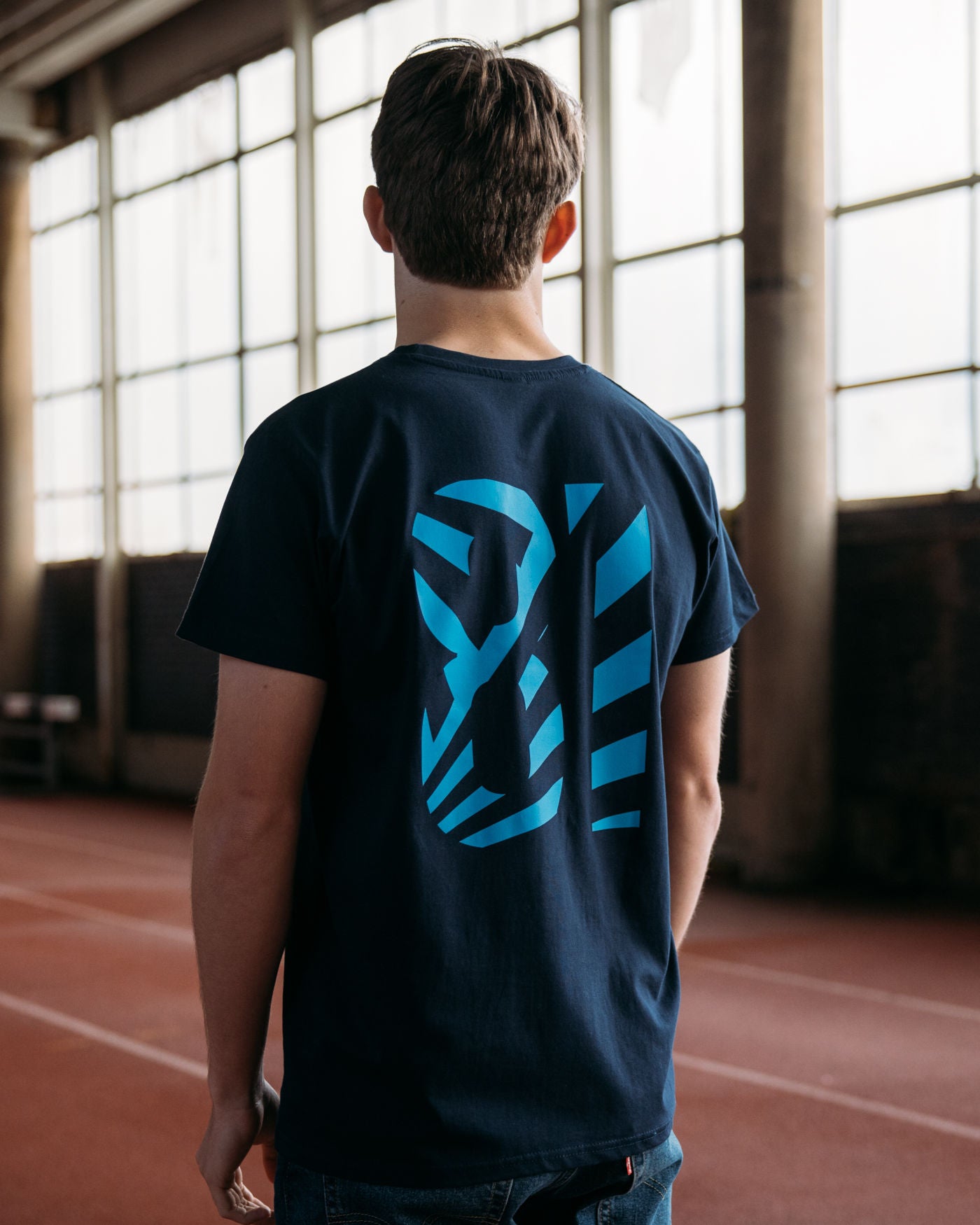 Man wearing the Keep Your Cool Navy T-Shirt featuring OP logo, F1 2024 season dates, and dazzle effect on the back, indoor setting.