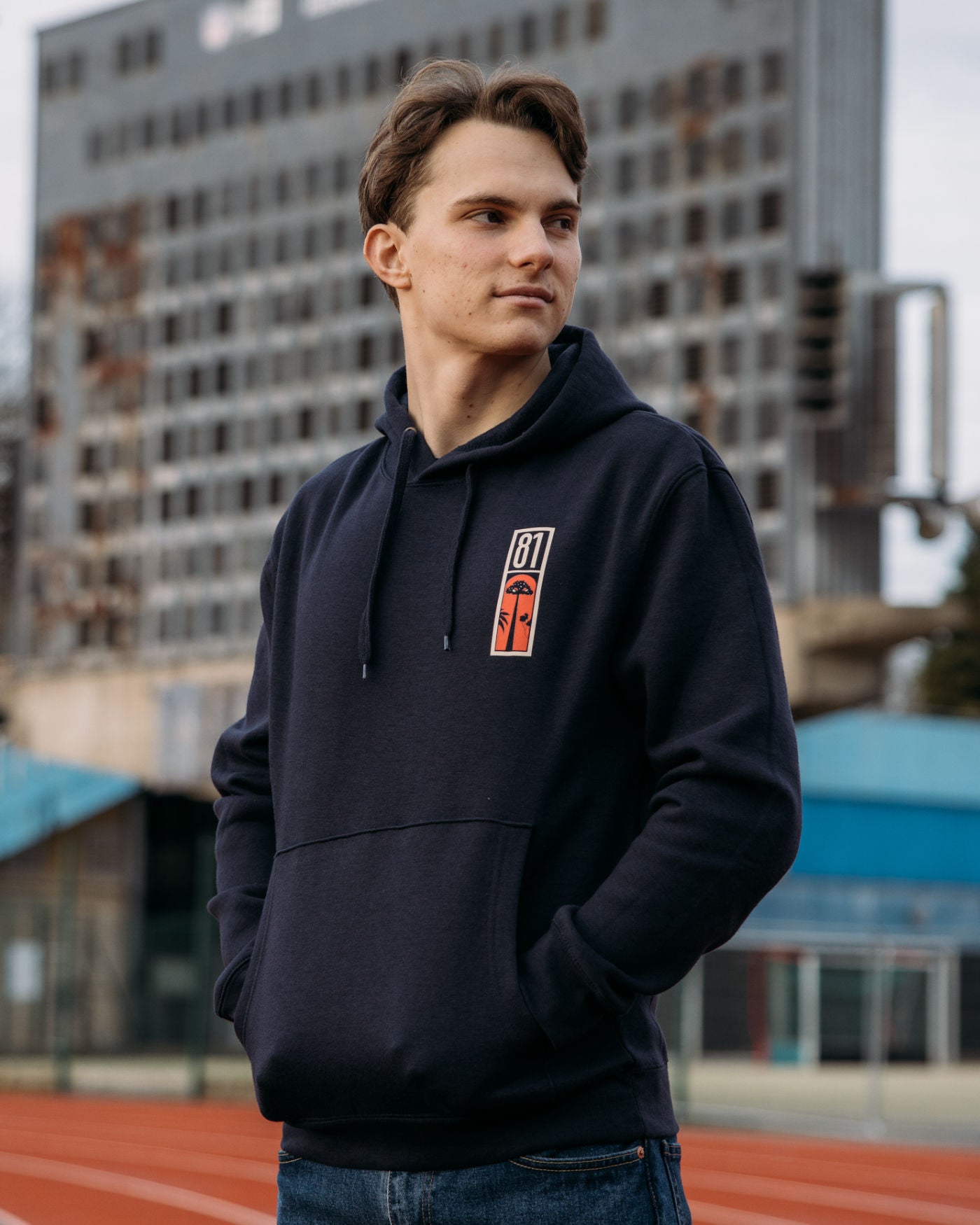 Person wearing Melbourne 2024 Hoodie inspired by F1 racing and Oscar Piastri, standing outdoors with urban backdrop.