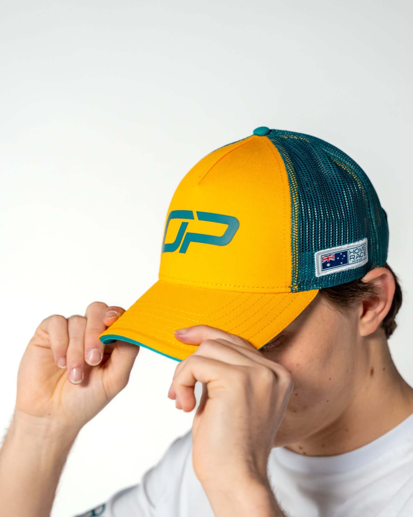 Home Race '26 Cap worn by Oscar, showcasing its vibrant green and gold colors and Oscar Piastri's OP design.