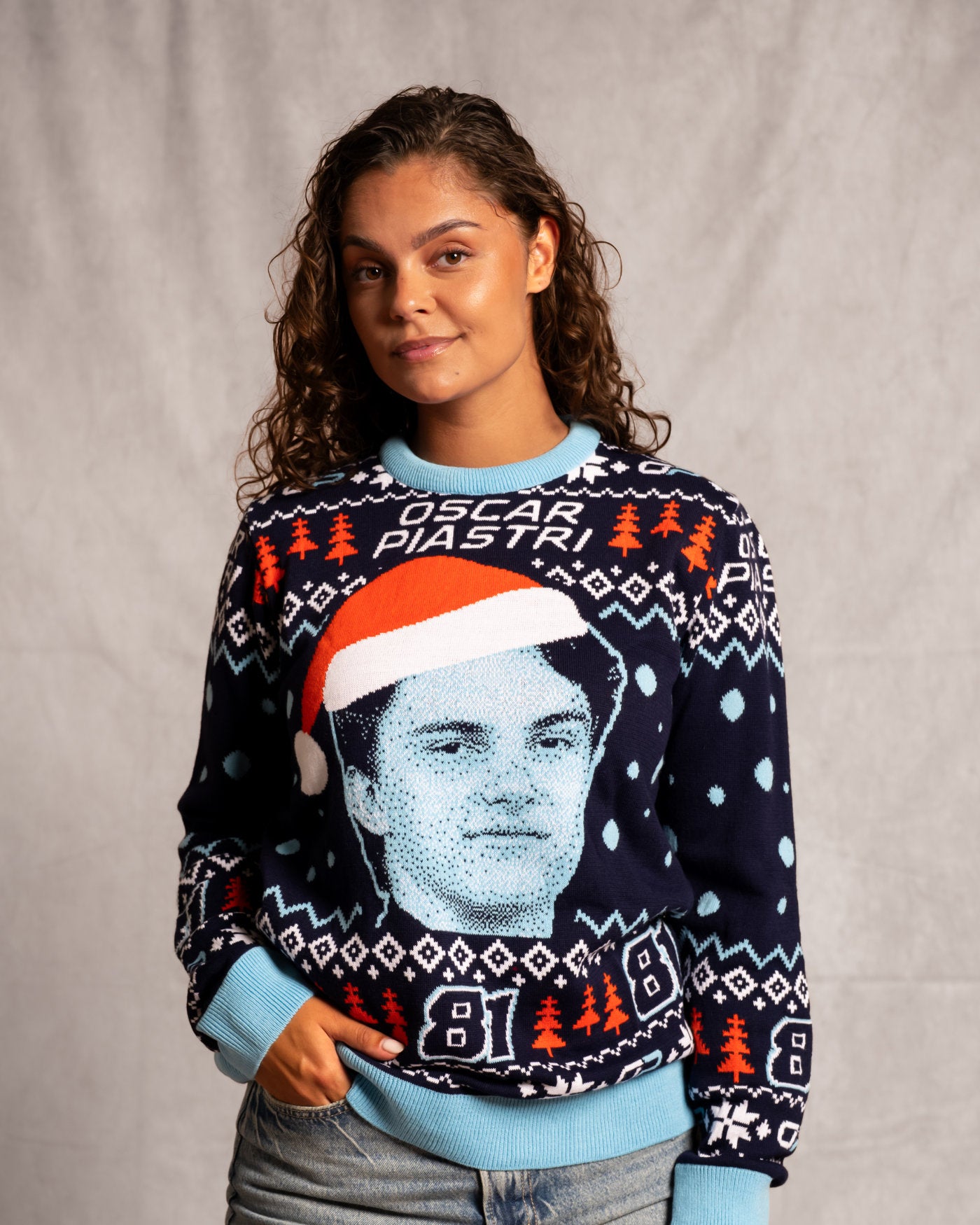 Woman wearing an Oscar Piastri Christmas sweater with festive design and Oscar's face, perfect for holiday celebrations.