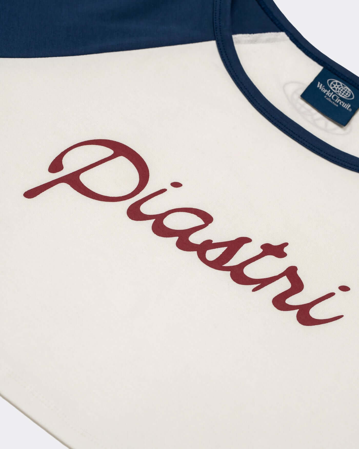 World Circuit Crop Tee featuring Piastri script on an off-white body with blue raglan sleeves.