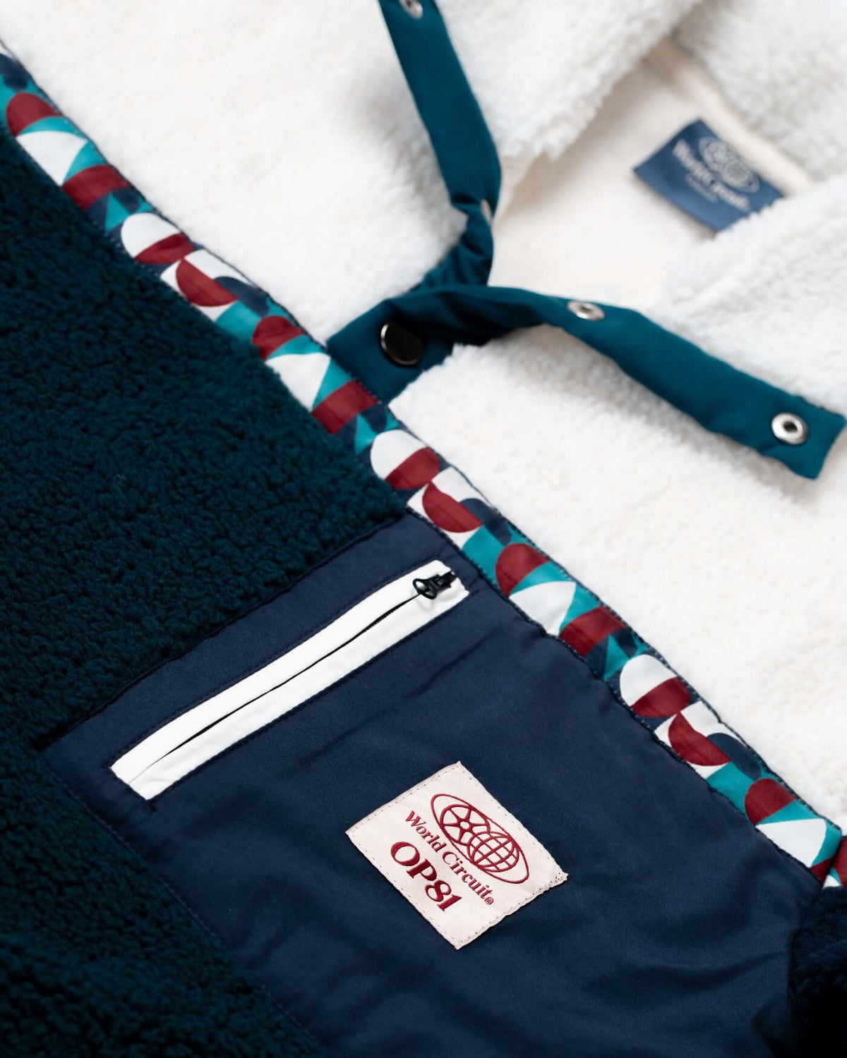 Close-up of the World Circuit Fleece showing half-button collar, zipped pocket, and custom jacquard tape detailing.