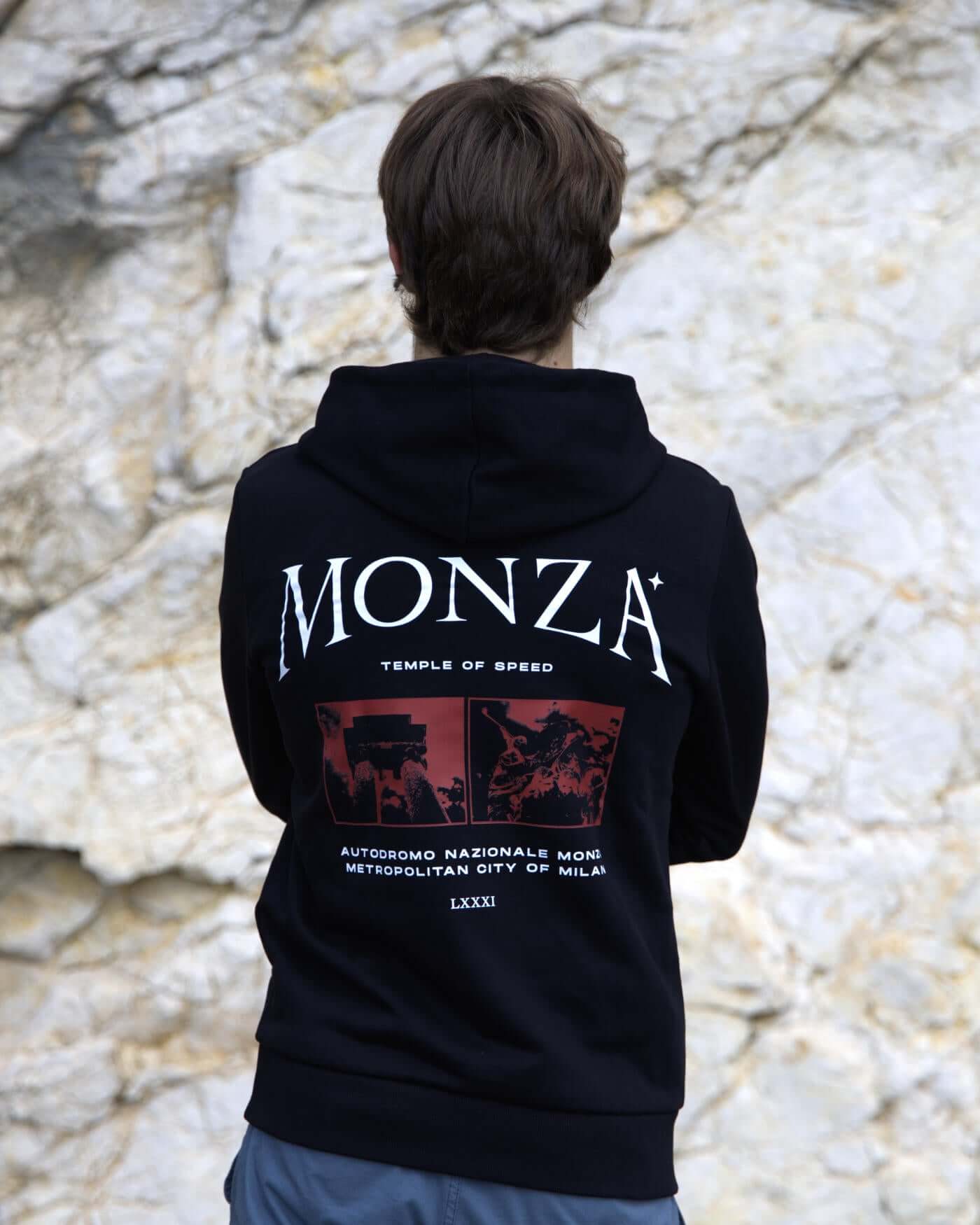 Unisex black Monza hoodie with "Temple of Speed" design, featuring kangaroo pocket, worn outdoors.