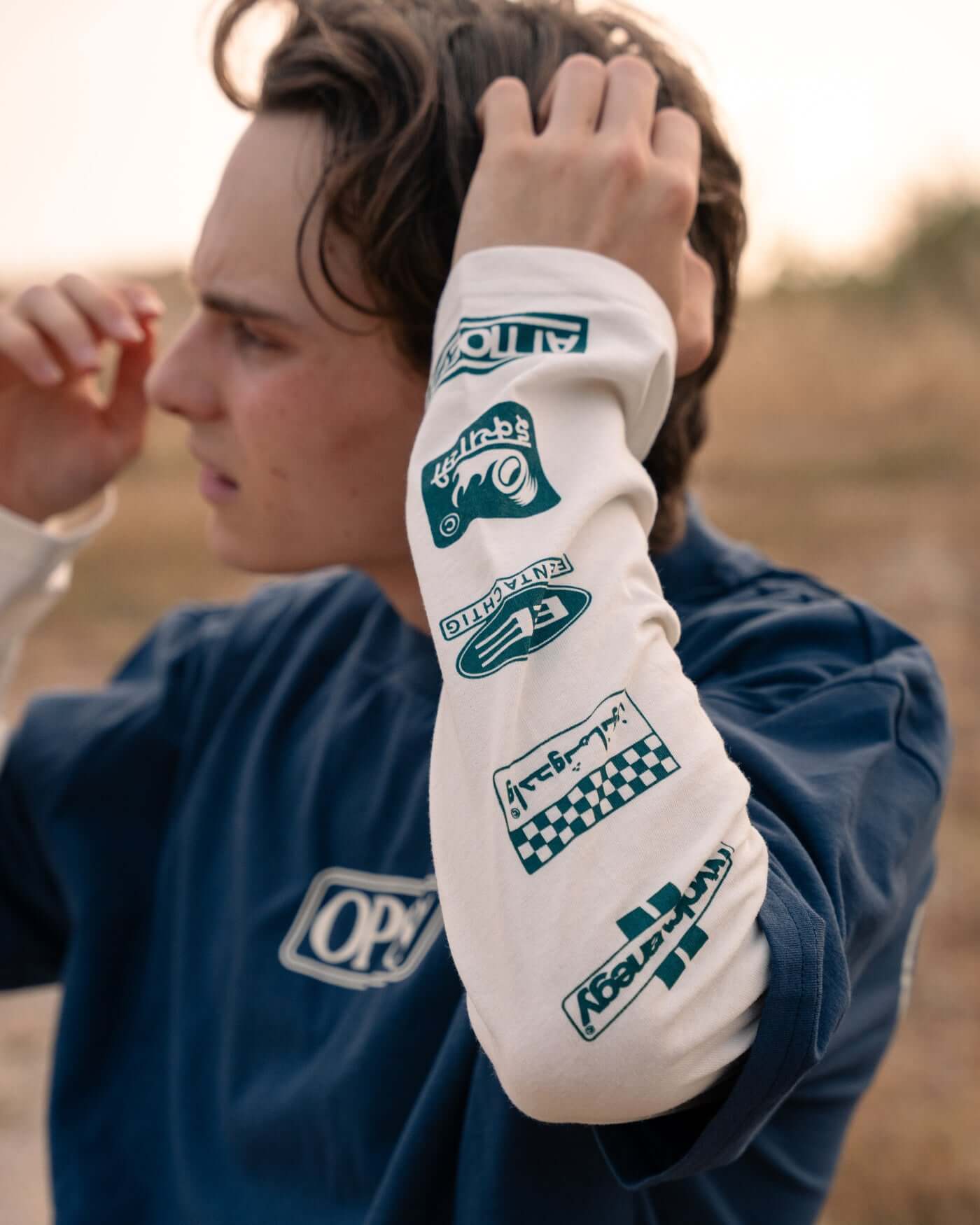 Oscar Piastri wears the World Circuit Layered T-Shirt - Blue showing off its layered design and sponsor graphics.