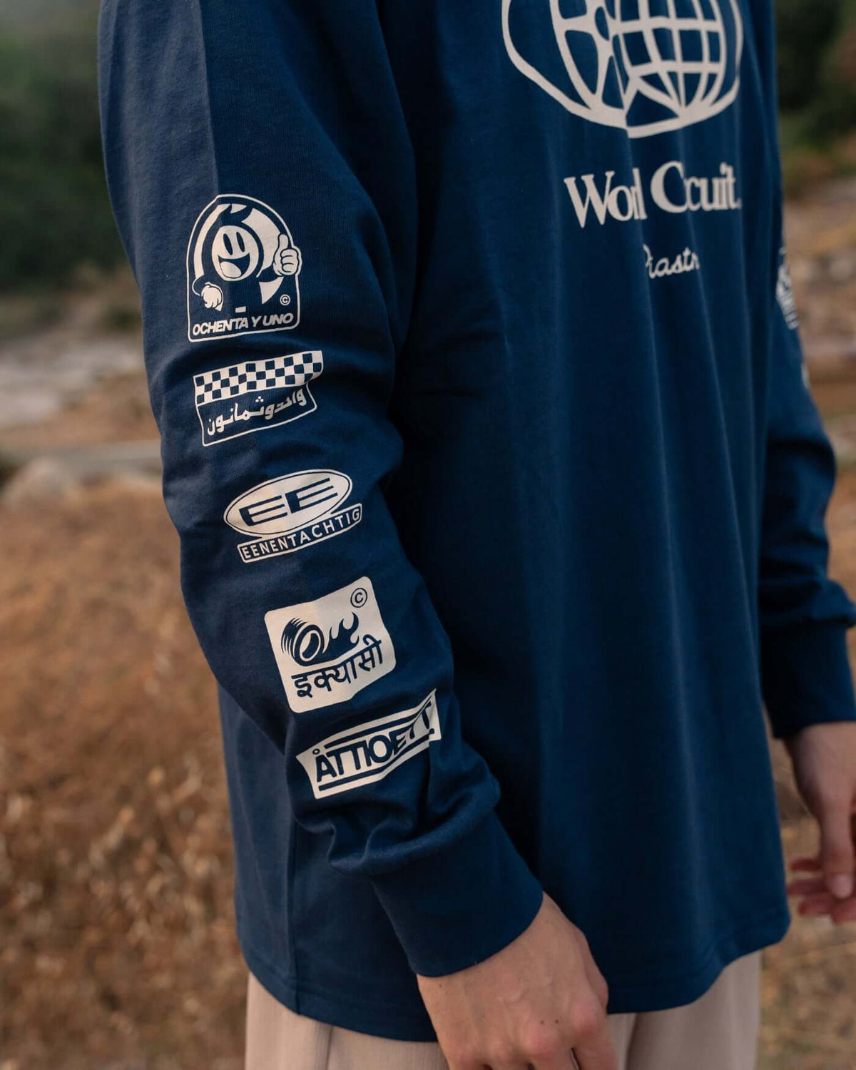 World Circuit Long Sleeve T-Shirt - Blue showcasing sleeve graphics on a model in a natural setting.