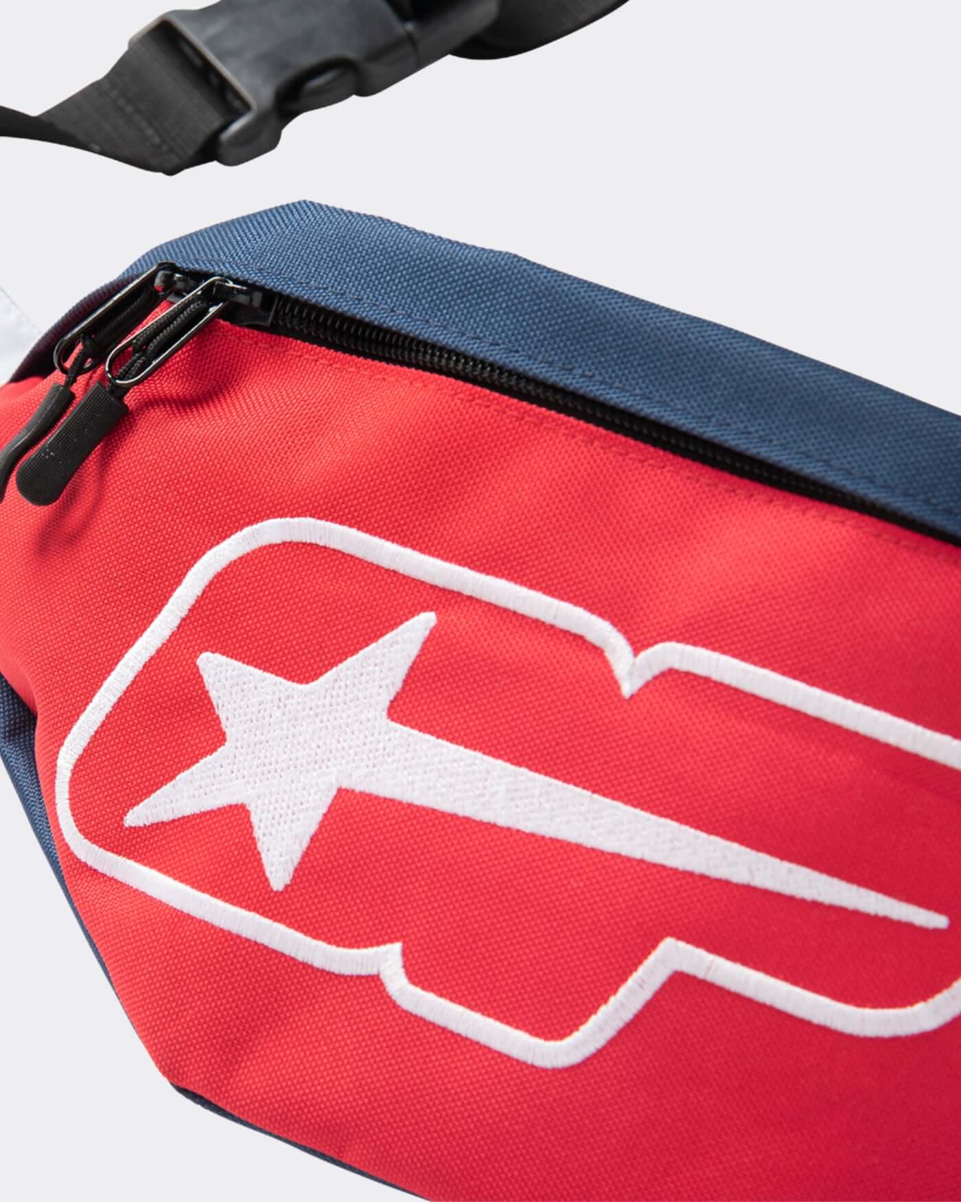 Close-up of the Origins Crossbody Bag showing bold red fabric and logo, perfect for hands-free style.