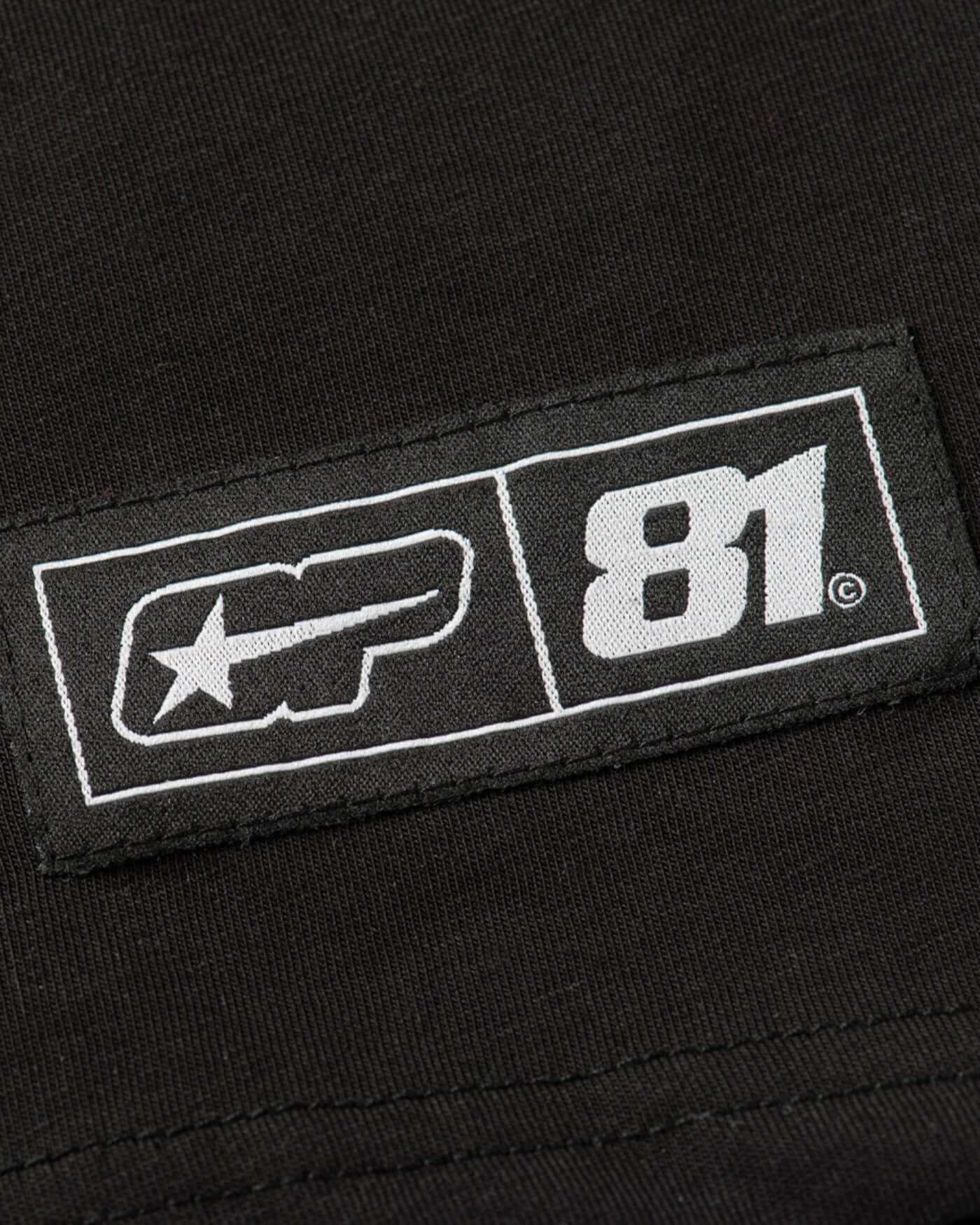 Close-up of the tag on the Origins Long Sleeve T-Shirt - Black featuring the logo and design details.