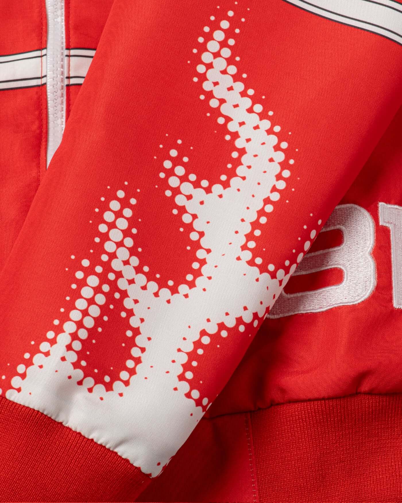 Close-up of the sleeve detailing on the Origins Race Jacket featuring bold graphics and retro style.