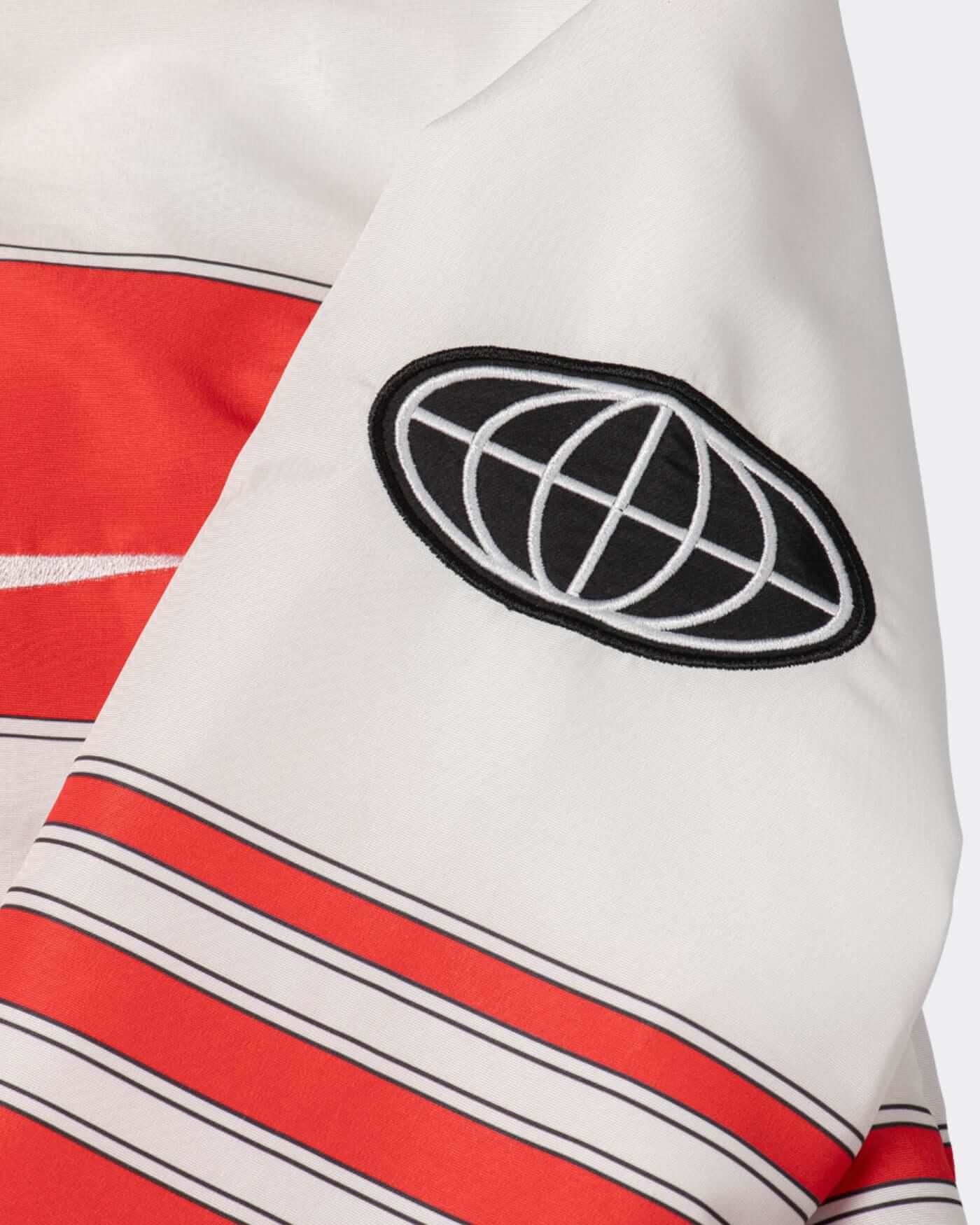 Close-up of the sleeve of the Origins Race Jacket featuring bold red stripes and a logo patch.