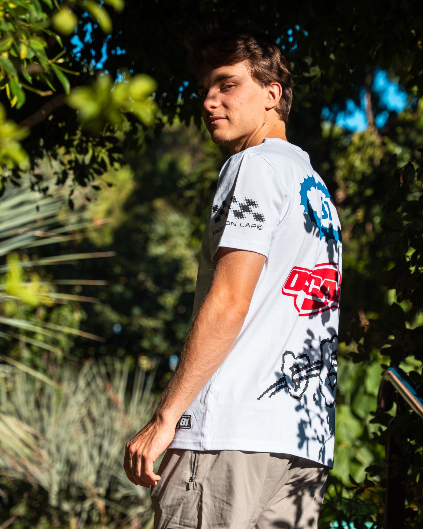 Origins T-Shirt - White worn by a Oscar outdoors, featuring bold graphics and a unisex design.