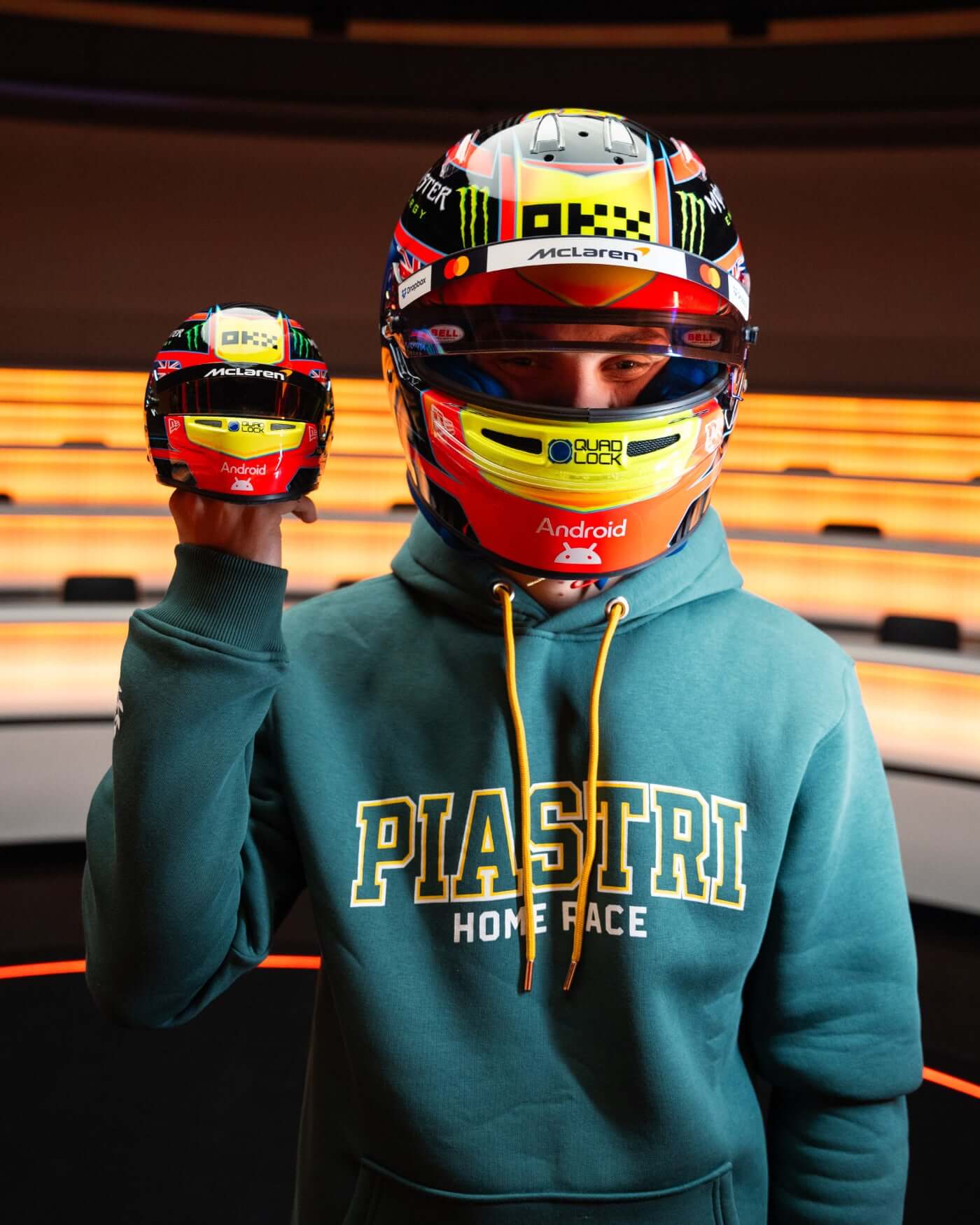 Oscar Piastri holding a 1:2 scale replica helmet, showcasing the striking design for the 2025 F1 season.