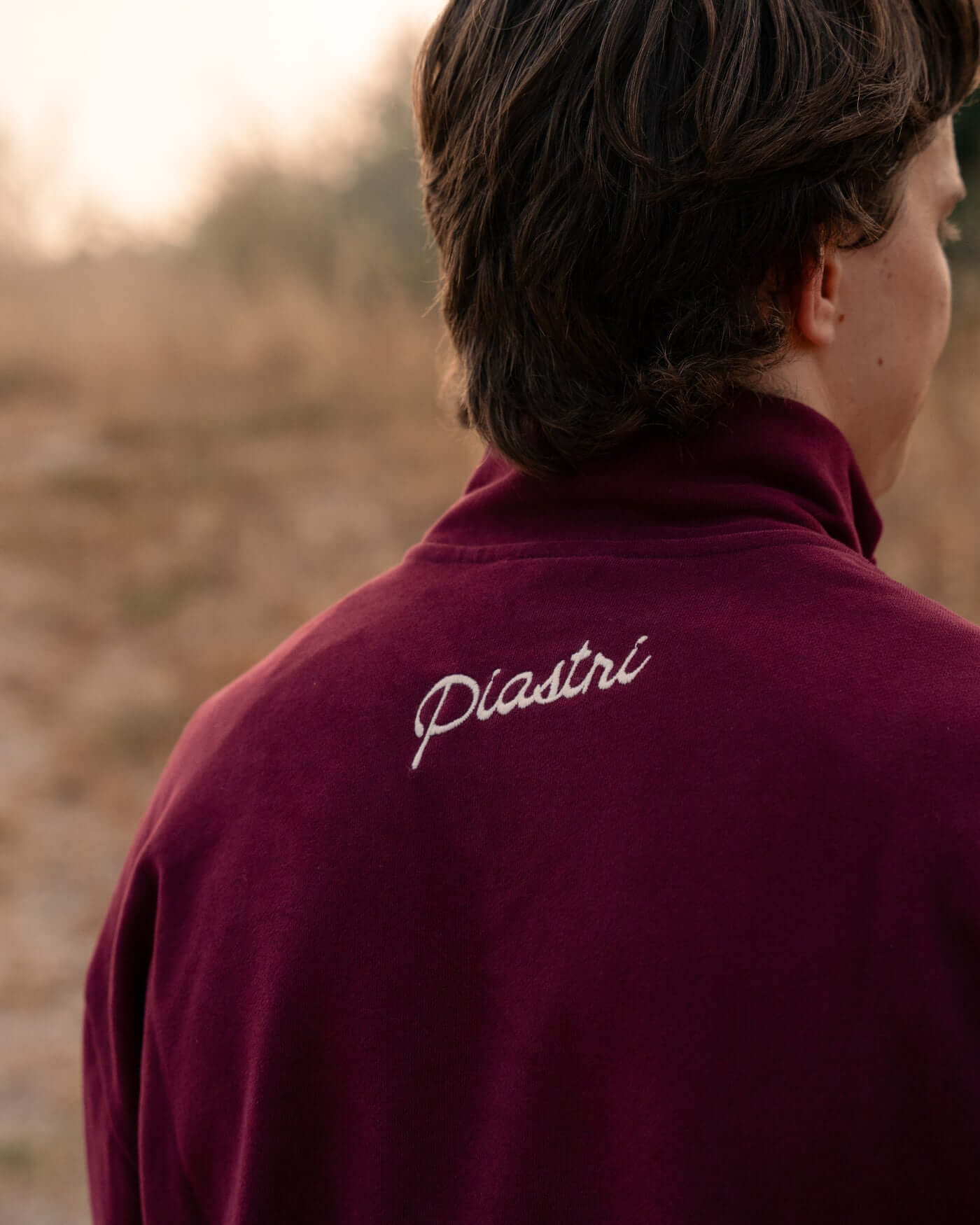 Back view of the World Circuit Quarter Zip - Burgundy showcasing the embroidered Piastri signature.