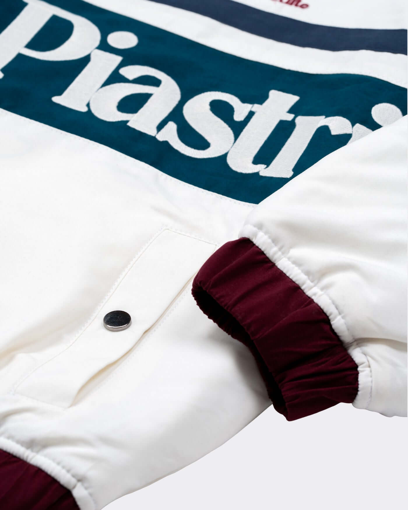 World Circuit Race Jacket close-up showing embroidered Piastri logo and burgundy ribbed cuffs