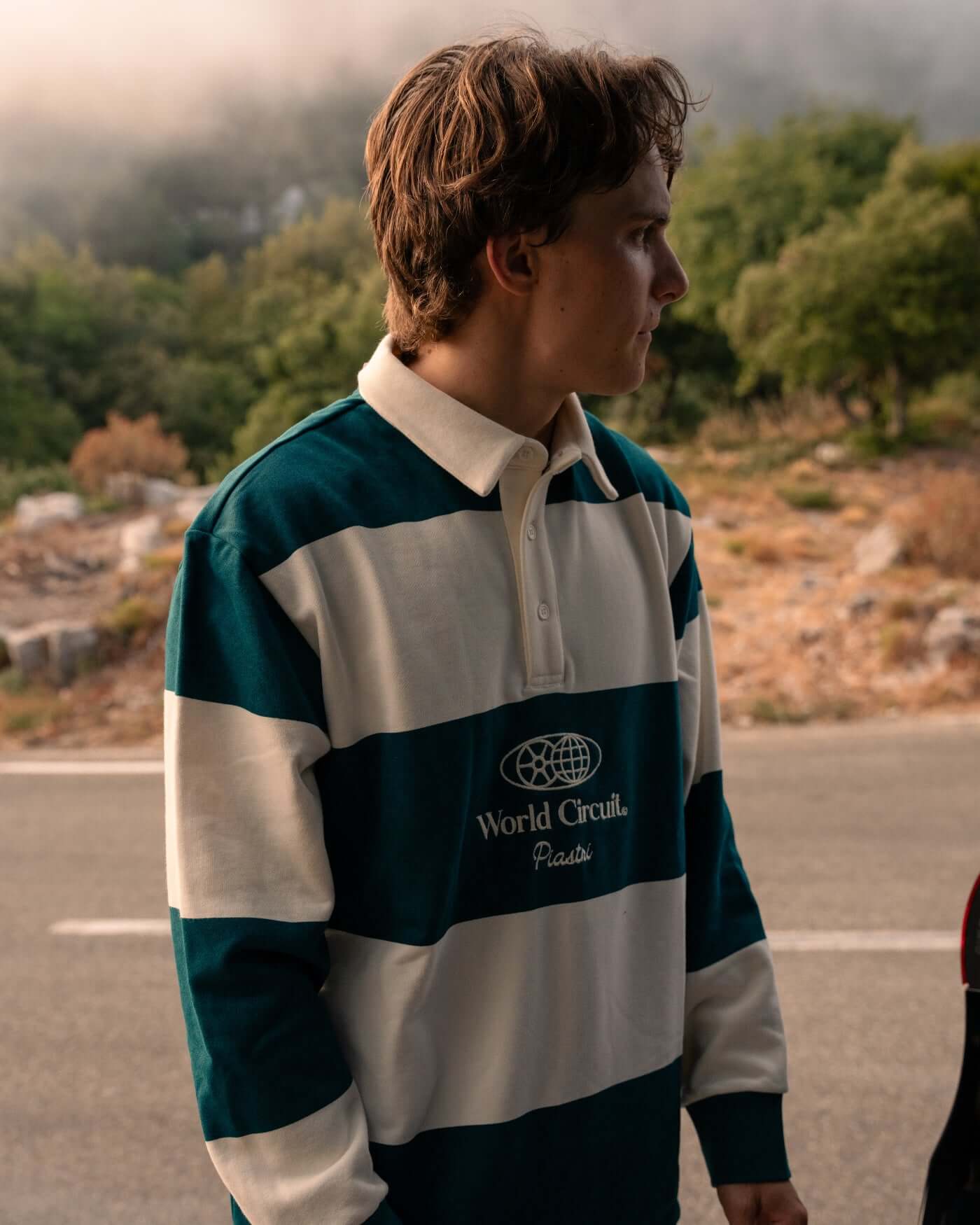 Profile view of a person wearing the World Circuit Rugby Shirt with green and off-white block stripes.