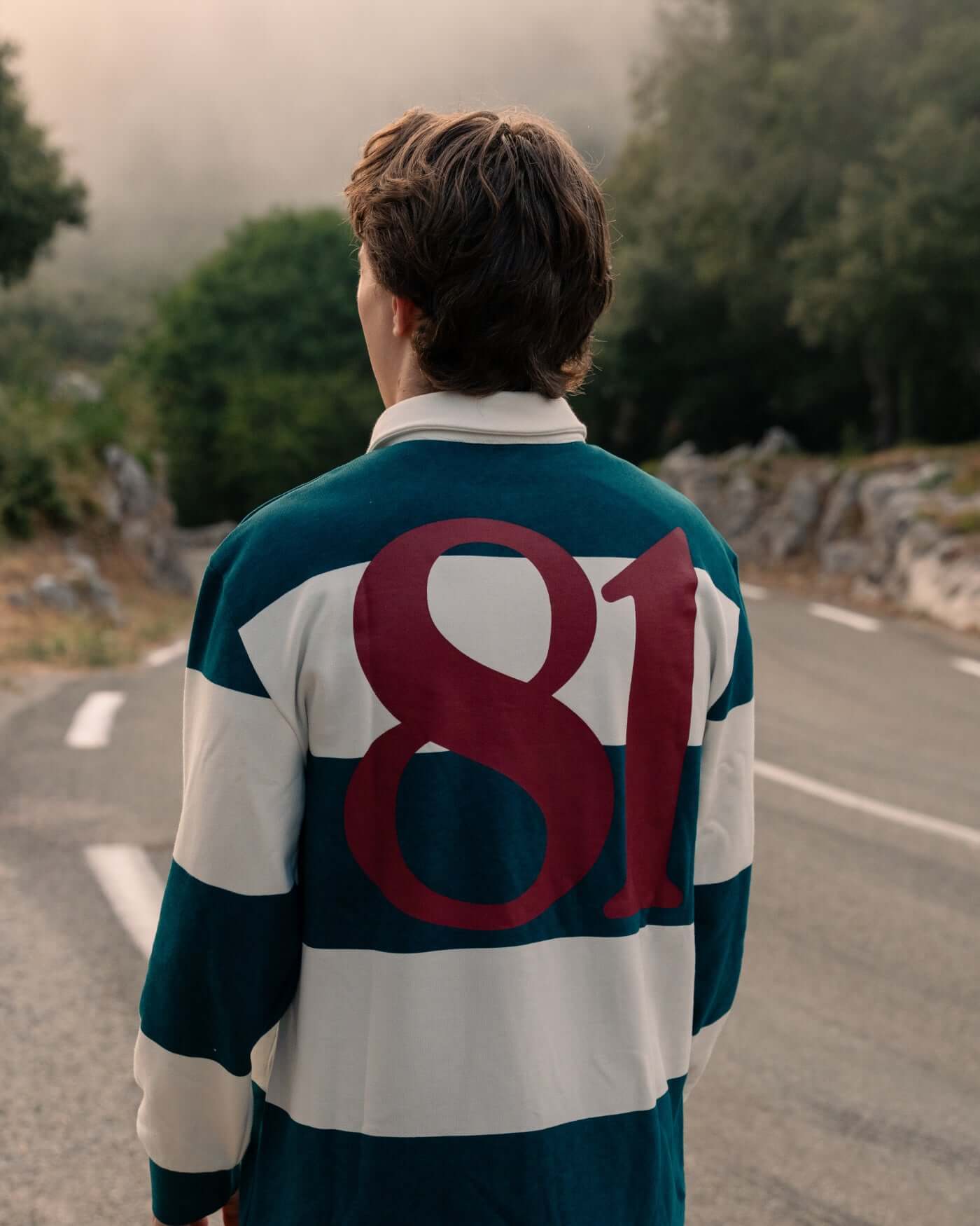 Back view of a person wearing a World Circuit Rugby Shirt with green and off-white stripes and the number 81 prominently featured.