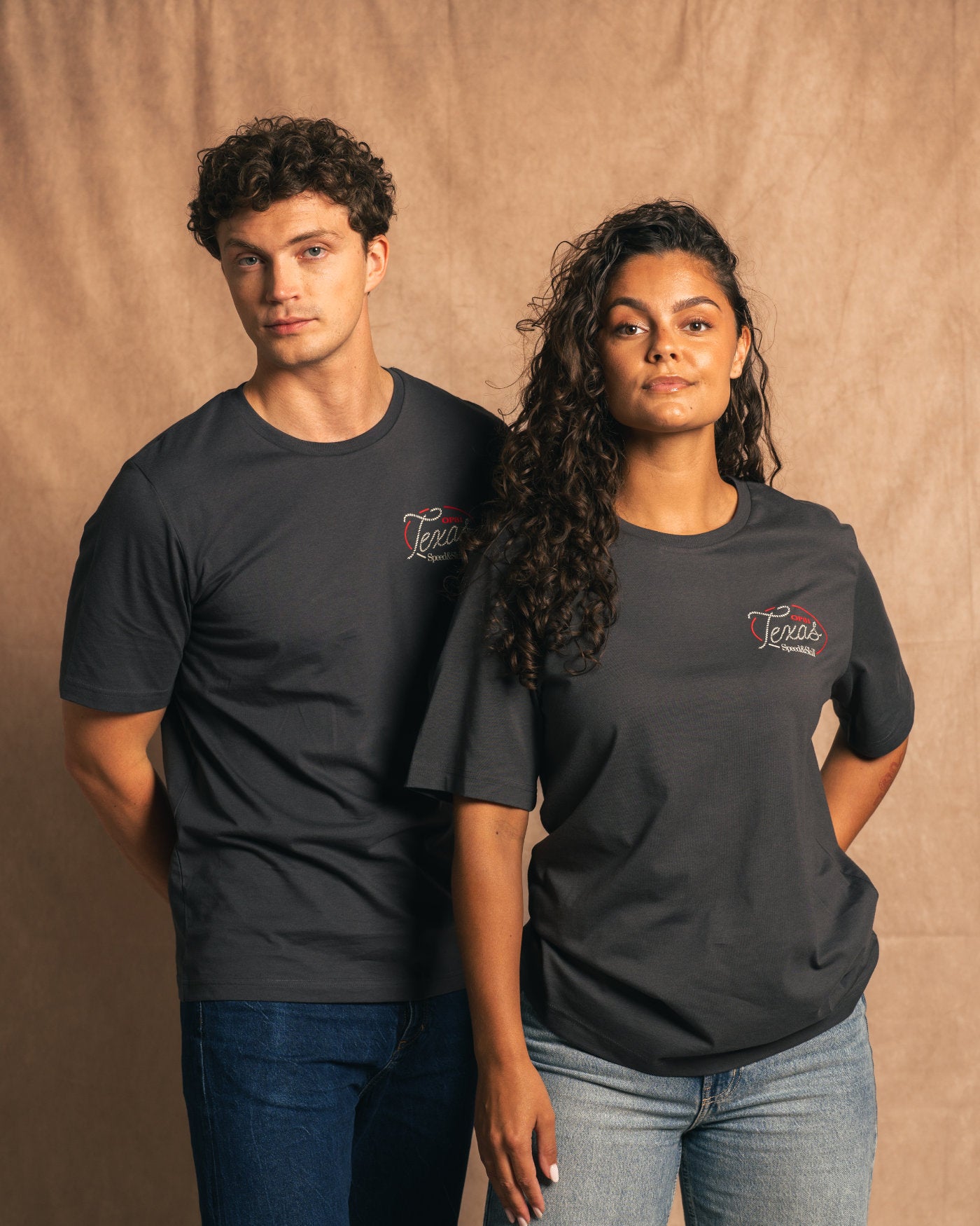 Two models wearing Texas 2024 T-Shirts in Asphalt with bold Texas-inspired graphics, celebrating Formula 1 and Wild West spirit.