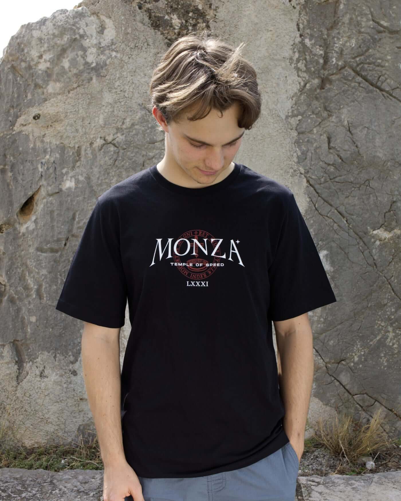 Oscar wearing a black Monza T-Shirt with "Temple of Speed" text, standing in front of a rock outdoor background.